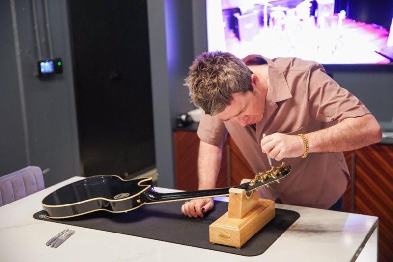 Noel Gallagher hand-signs the Gibson ’78 Les Paul Custom guitars.